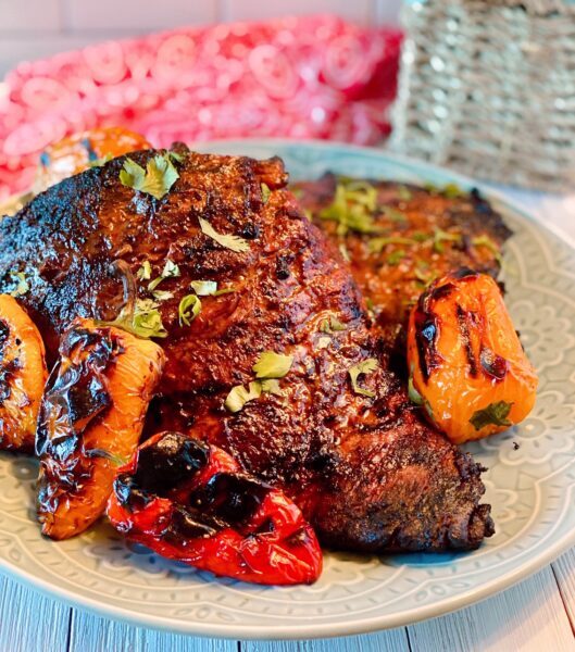 Grilled whole skirt steak on a plate with roasted peppers 