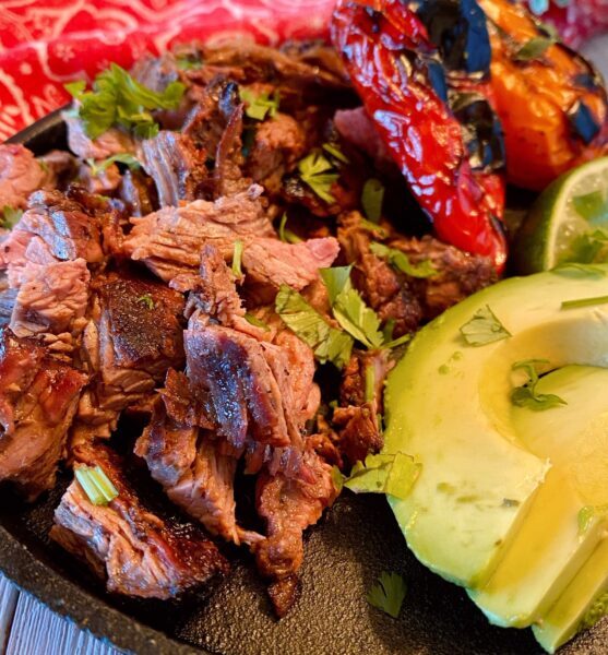 Chopped Carne Asada on a plate with roasted peppers and avocado. 