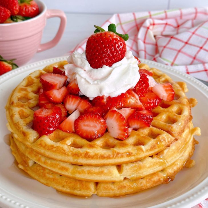 Stacked Waffles with fresh strawberries and whipped cream.