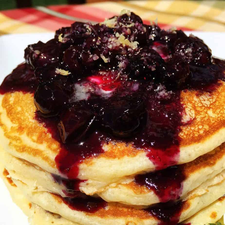Stack of buttermilk pancakes with fresh blueberry sauce on top.
