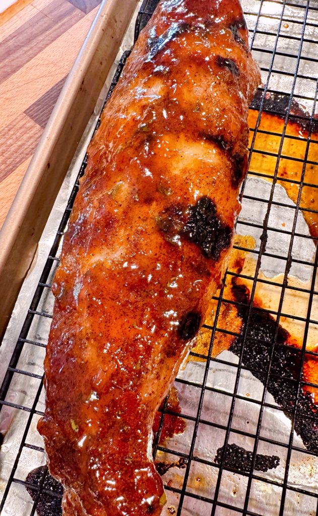 Grilled pork tenderloin on a rack over a baking sheet.