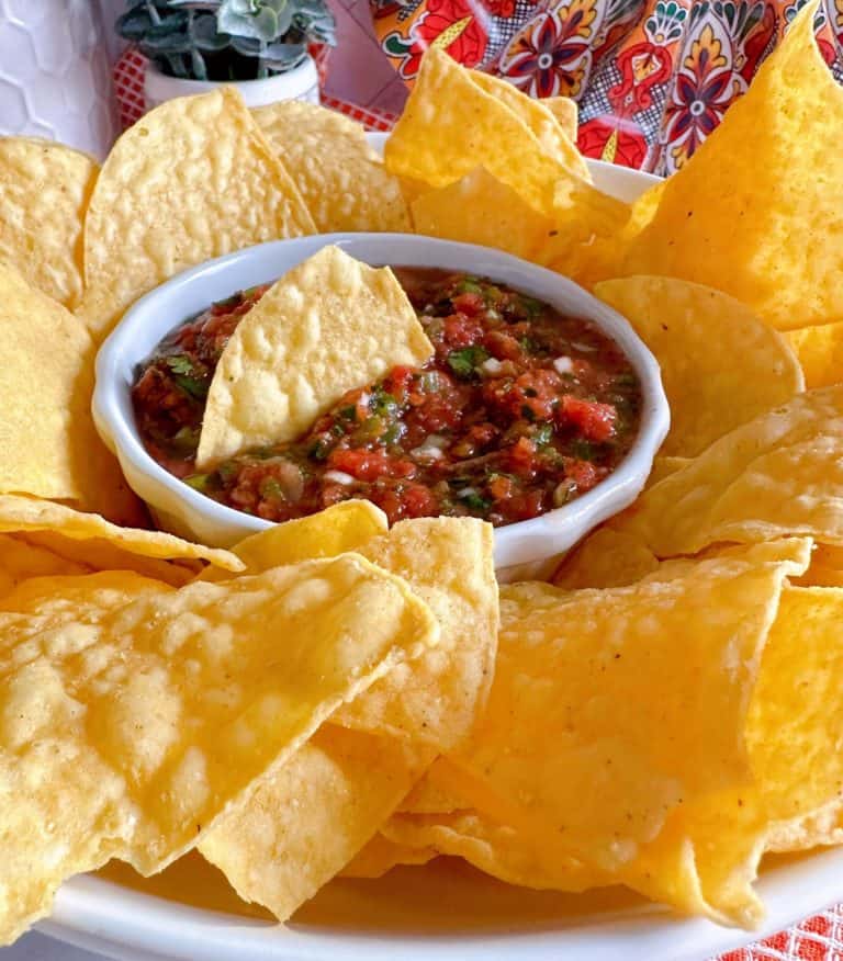 Fresh Salsa with a chip in the dip surrounded by other corn chips.