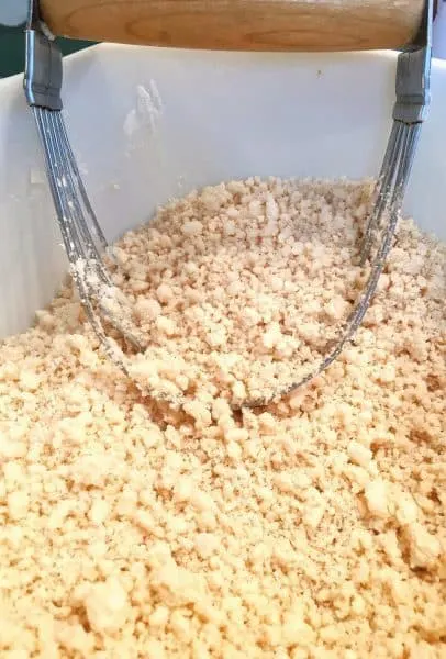 Shortening being cut into flour and salt for a flaky pie crust for Strawberry Rhubarb Pie.