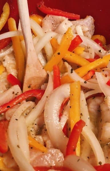 Chicken strips, pepper, and onions for Chicken Fajita's marinating in a large bowl with the tangy marinade.