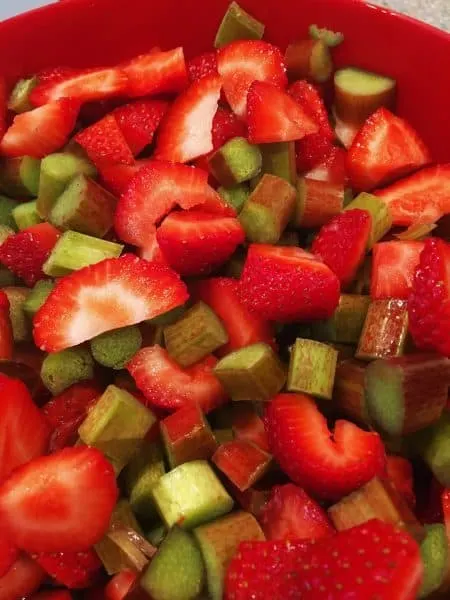 A large bowl filled with chopped fresh rhubarb and sliced fresh strawberries. The start to an amazing filling for Strawberry Rhubarb Pie.