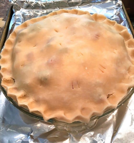 Unbaked Rhubarb and Strawberry Pie on lined baking sheet ready to bake.