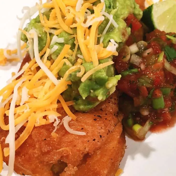 Homemade chili relleno topped with homemade salsa, guacamole, and cheese