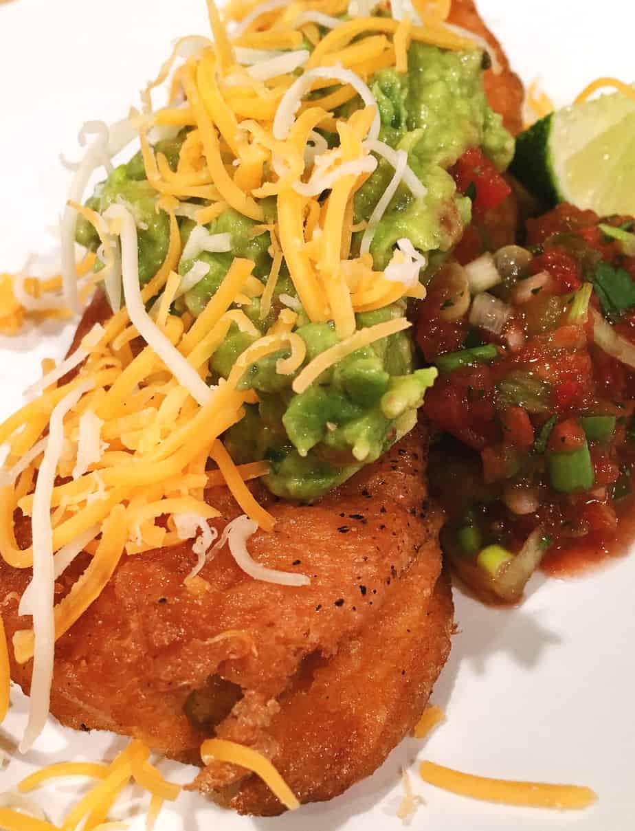 Homemade chili relleno topped with homemade salsa, guacamole, and cheese