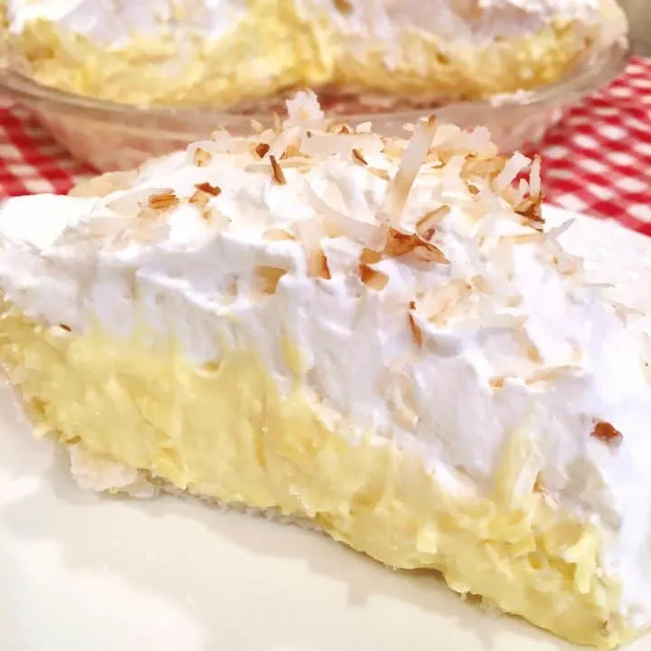 A large slice of easy Coconut Cream Pie on a white plate ready to eat!