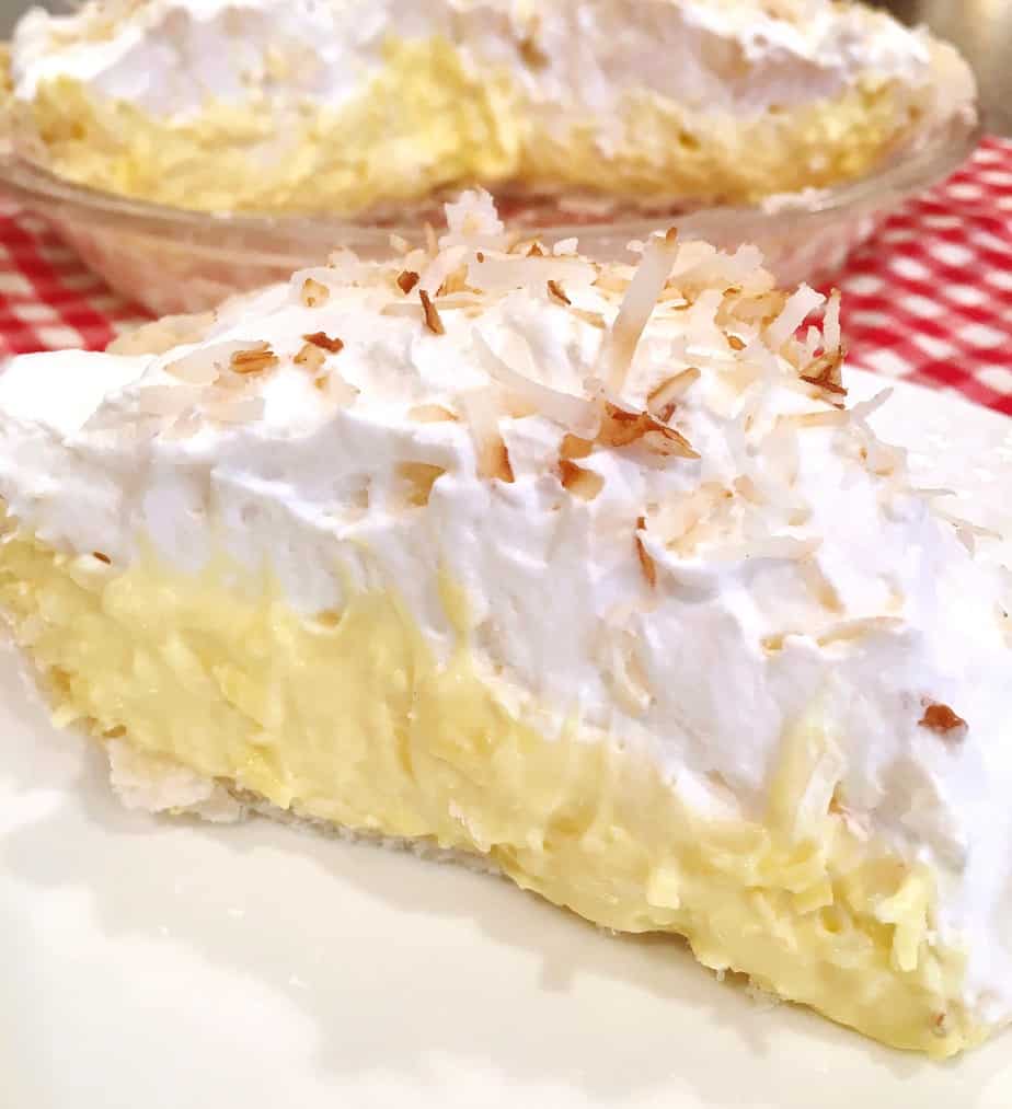 A large slice of easy Coconut Cream Pie on a white plate ready to eat!