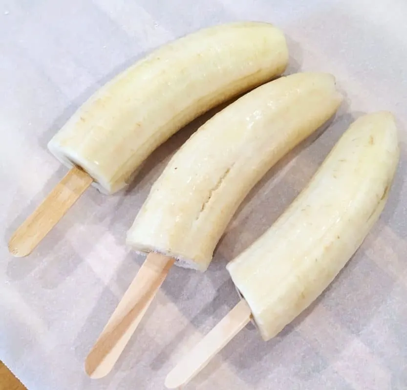Banana's cut in half with popsicles in the ends, frozen.