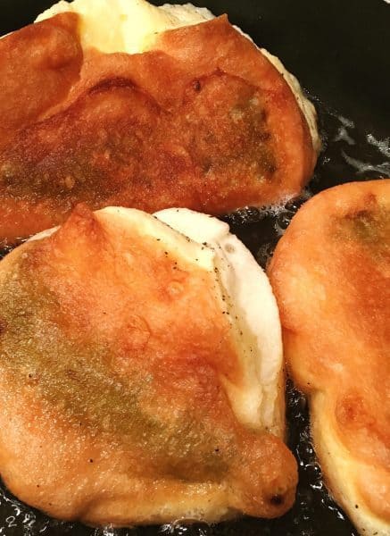 Chili Relleno's turned over and golden brown in frying pan with hot oil.