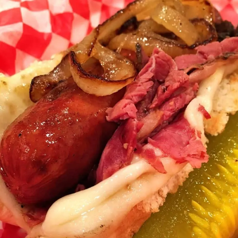 All beef grilled hot dog topped with onions and pastrami in a toasted bun with melted cheese. Side pickle.