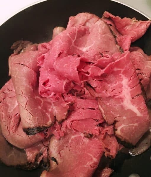 Roast Beef in hot skillet warming up for sandwiches.