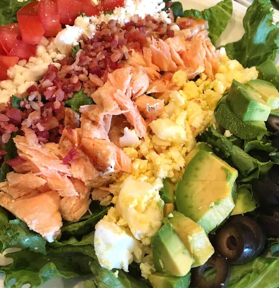 Plate filled with rows of delicious cobb salad toppings including delicious salmon