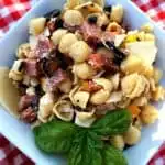 Bowl full of antipasto pasta salad with fresh basil.