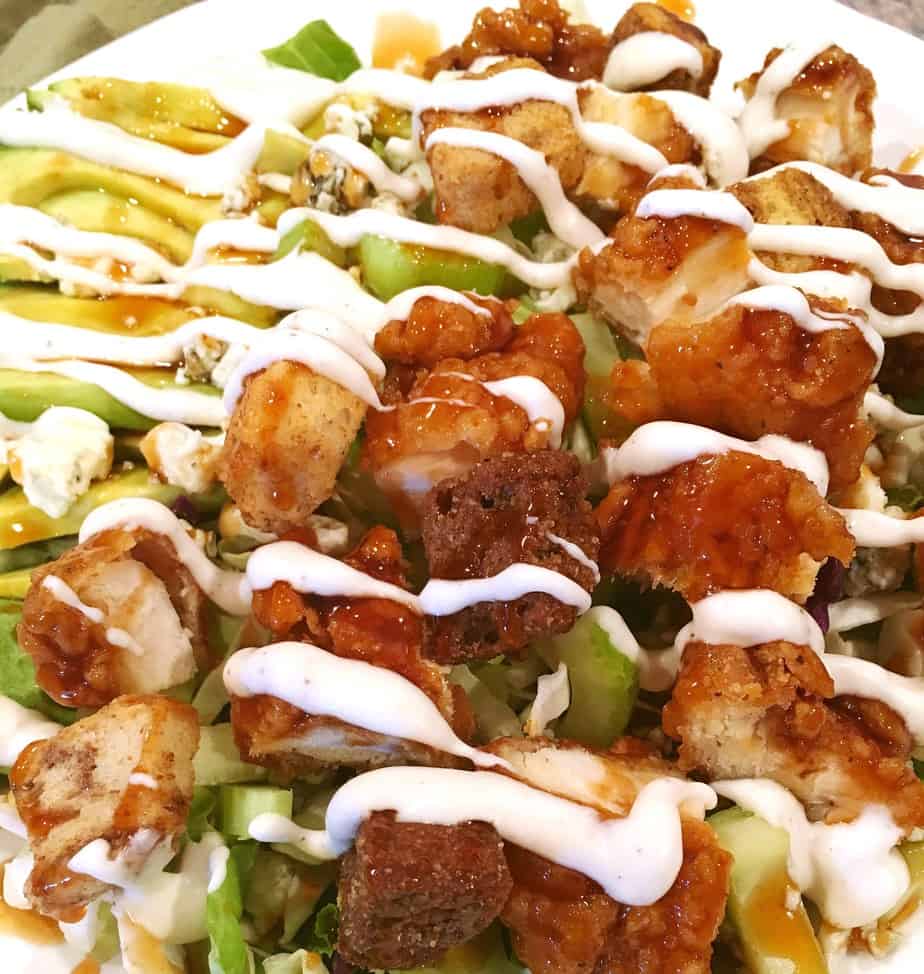 A green salad with cut up boneless buffalo wings