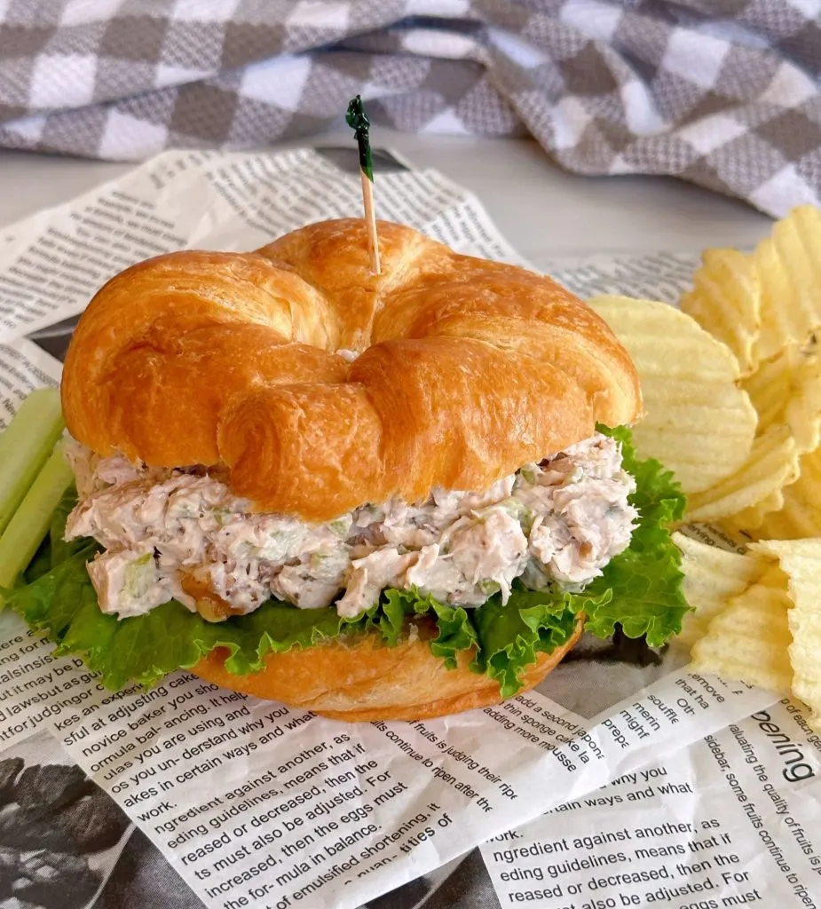 Chicken Salad Sandwich on a croissant rolls with chips.