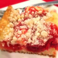A slice of cake with cherrys and crumbled sugar mixed in