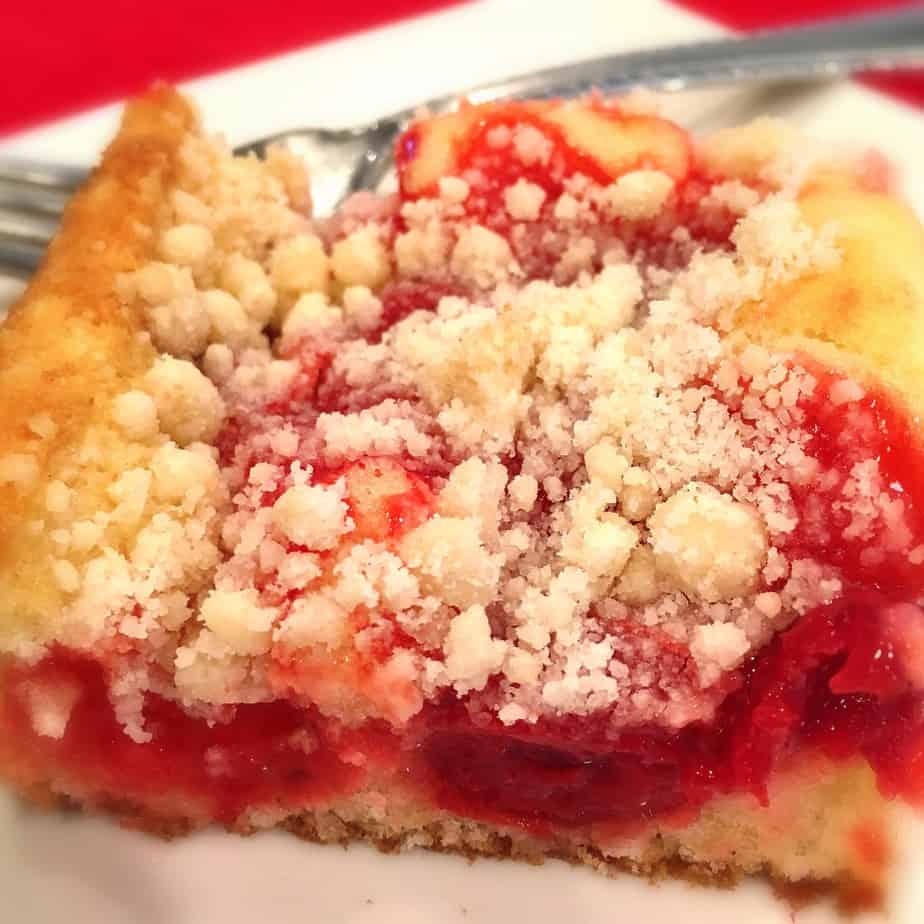 een plakje cake met cherrys en verkruimelde suiker gemengd in