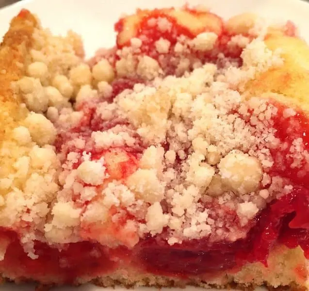 Big slice of cherry crumb coffee cake with layers of delicious cherries on top of a moist cake.
