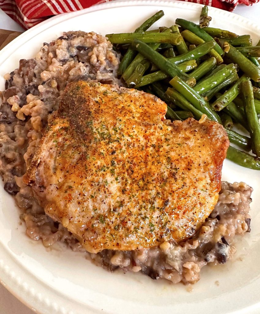 Minnesota Pork Chop with wild rice on a plate and a side of green beans.