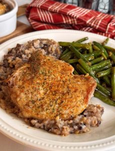 White plate with Minnesota Pork Chop Casserole and fresh green beans.