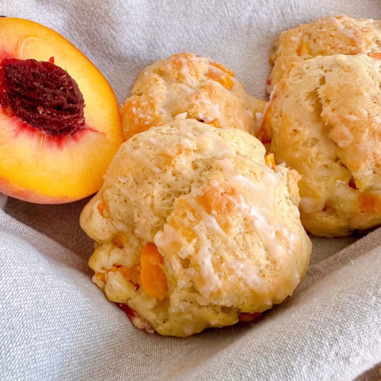 Fresh Peach Scones in a basket with a fresh peach.