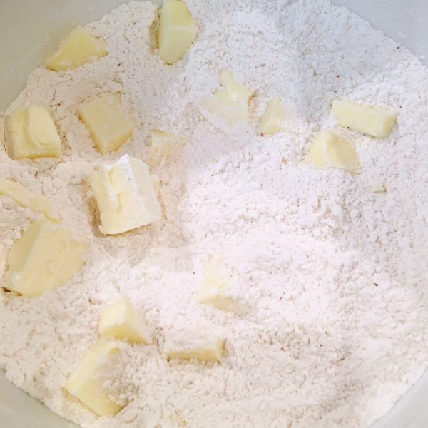 The butter being cut into the dry ingredients