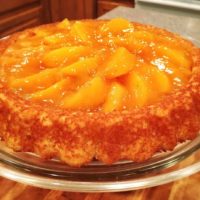 A cake with fresh peach slices and a golden glaze