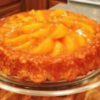 A cake with fresh peach slices and a golden glaze