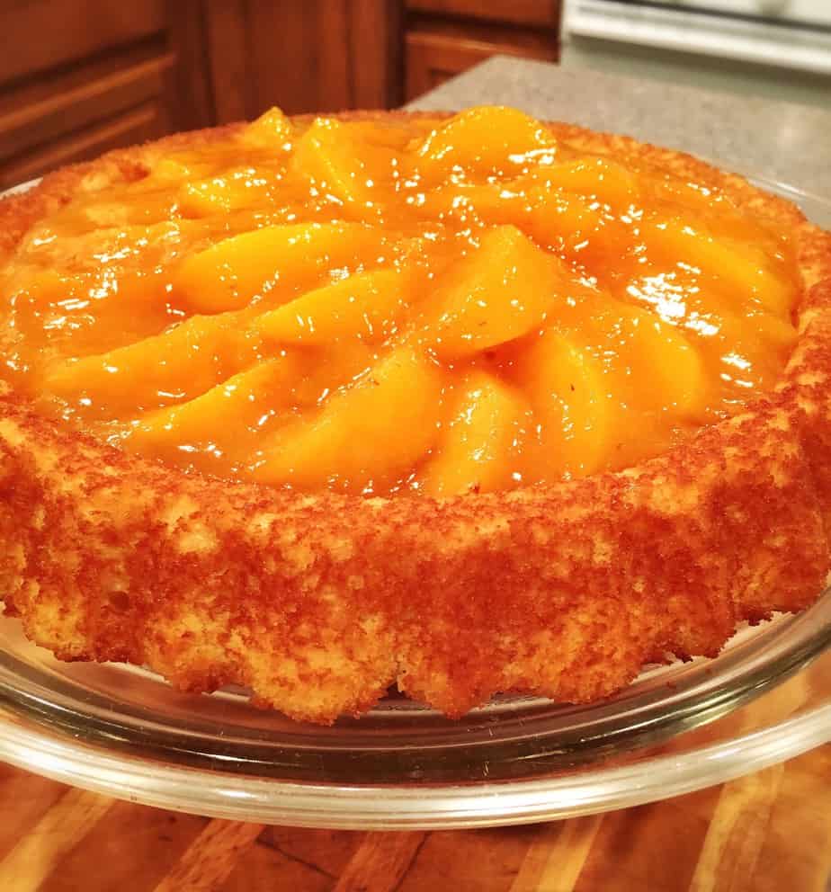 A cake with fresh peach slices and a golden glaze