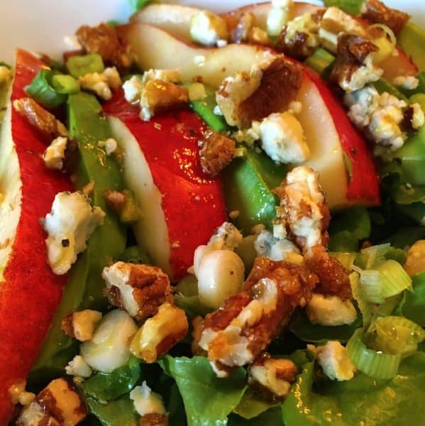 A green salad with sliced pears,nuts, avocado and blue cheese
