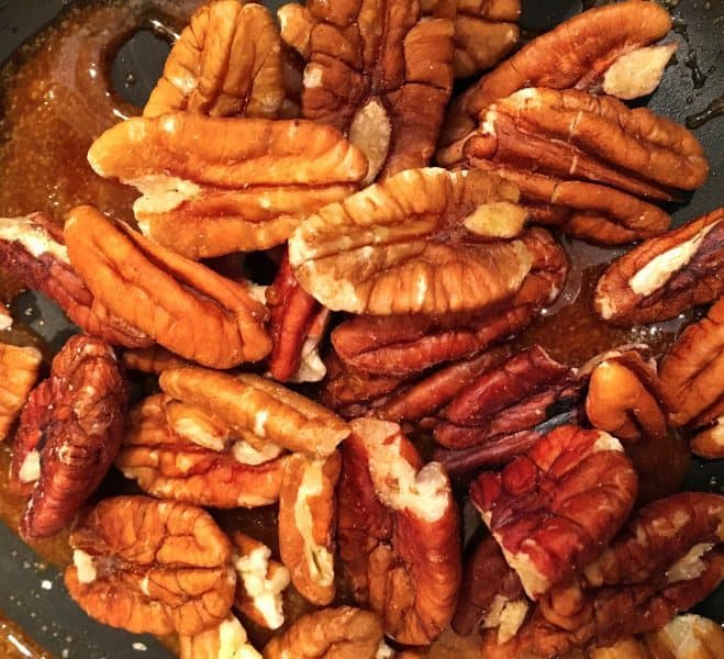 Adding pecan halves to melted sugar.