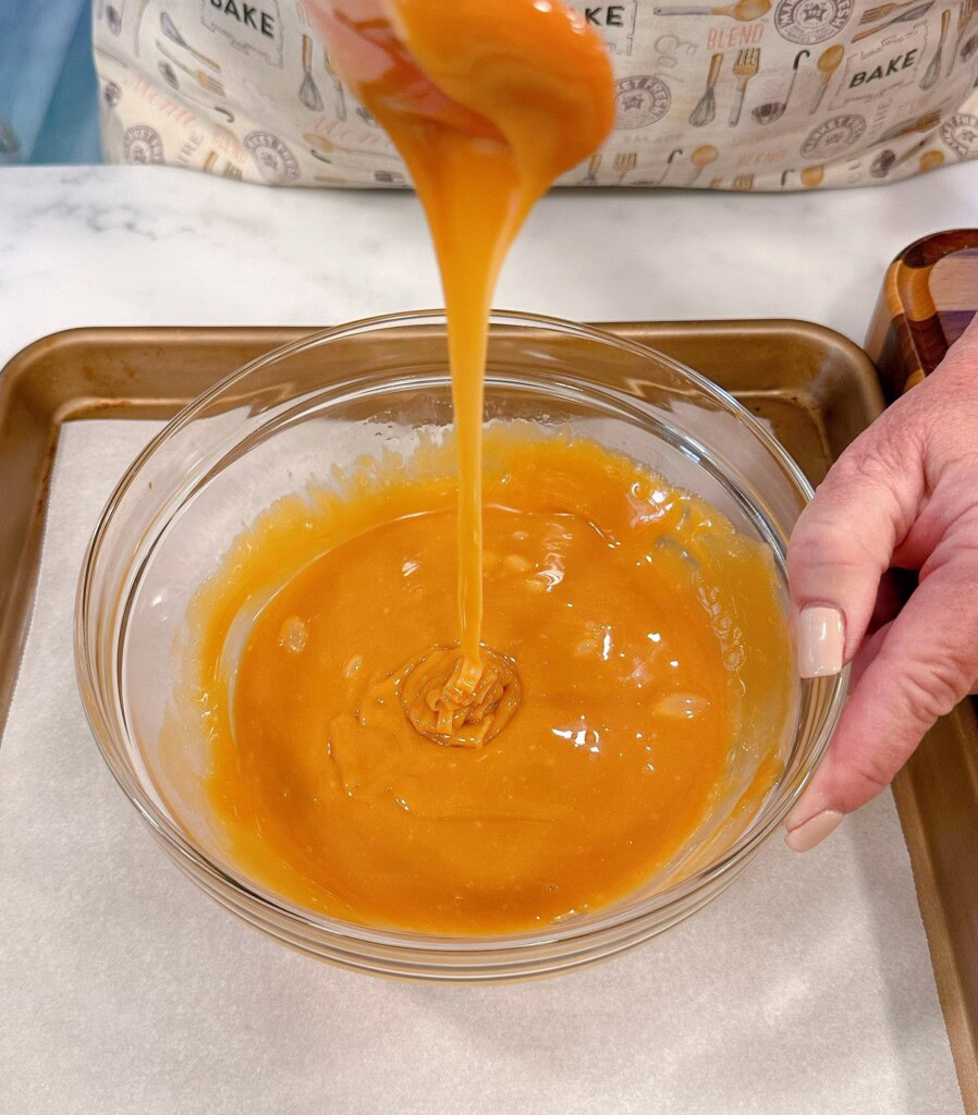 Melted caramel in a bowl on top of the baking sheet with parchment.