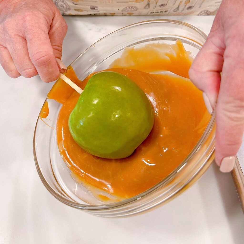 Dipping the caramel apples in the hot melted caramel.