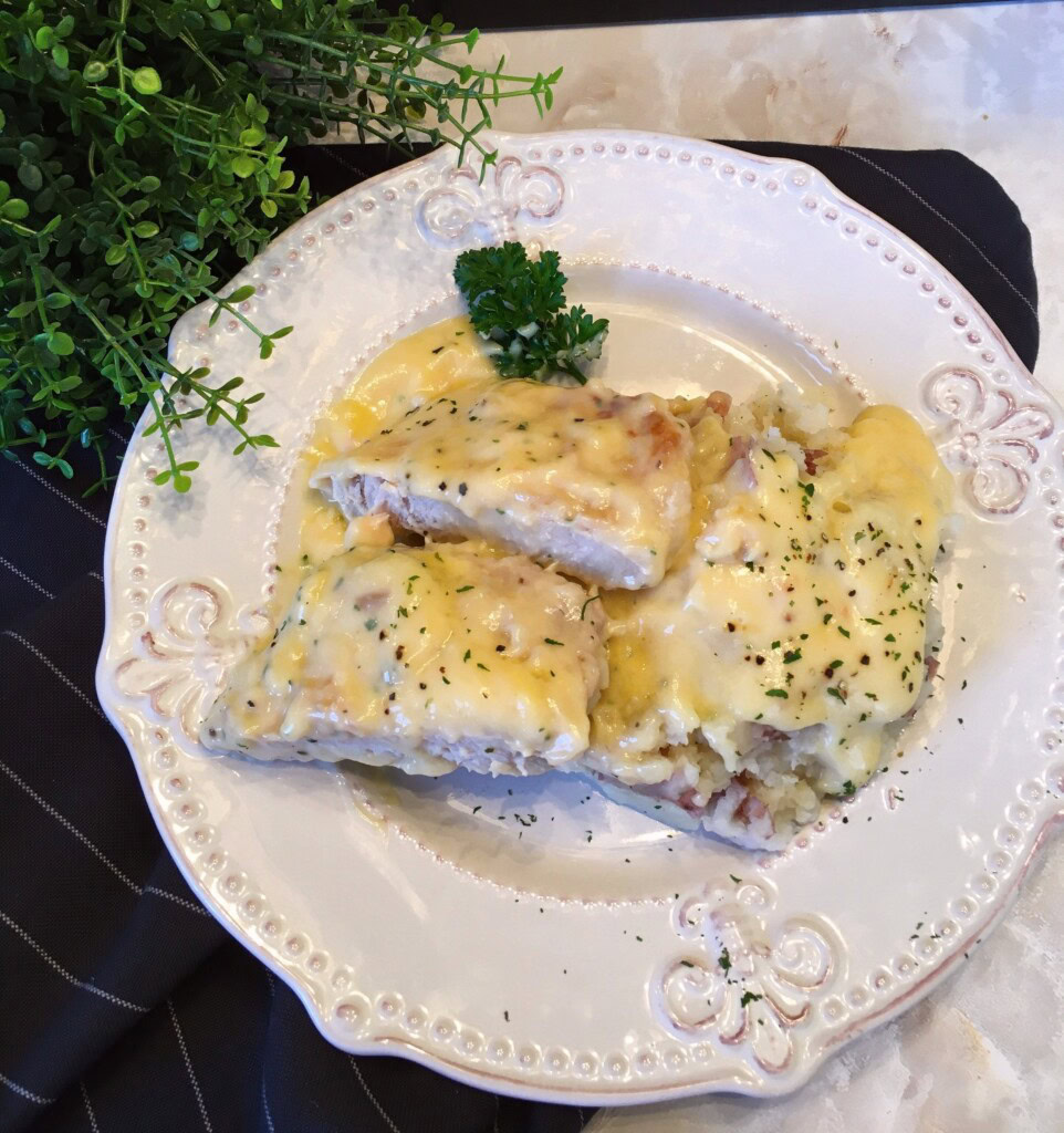 A dinner plate with mashed potatoes and a cut slow cooker chicken fried pork chop on top.