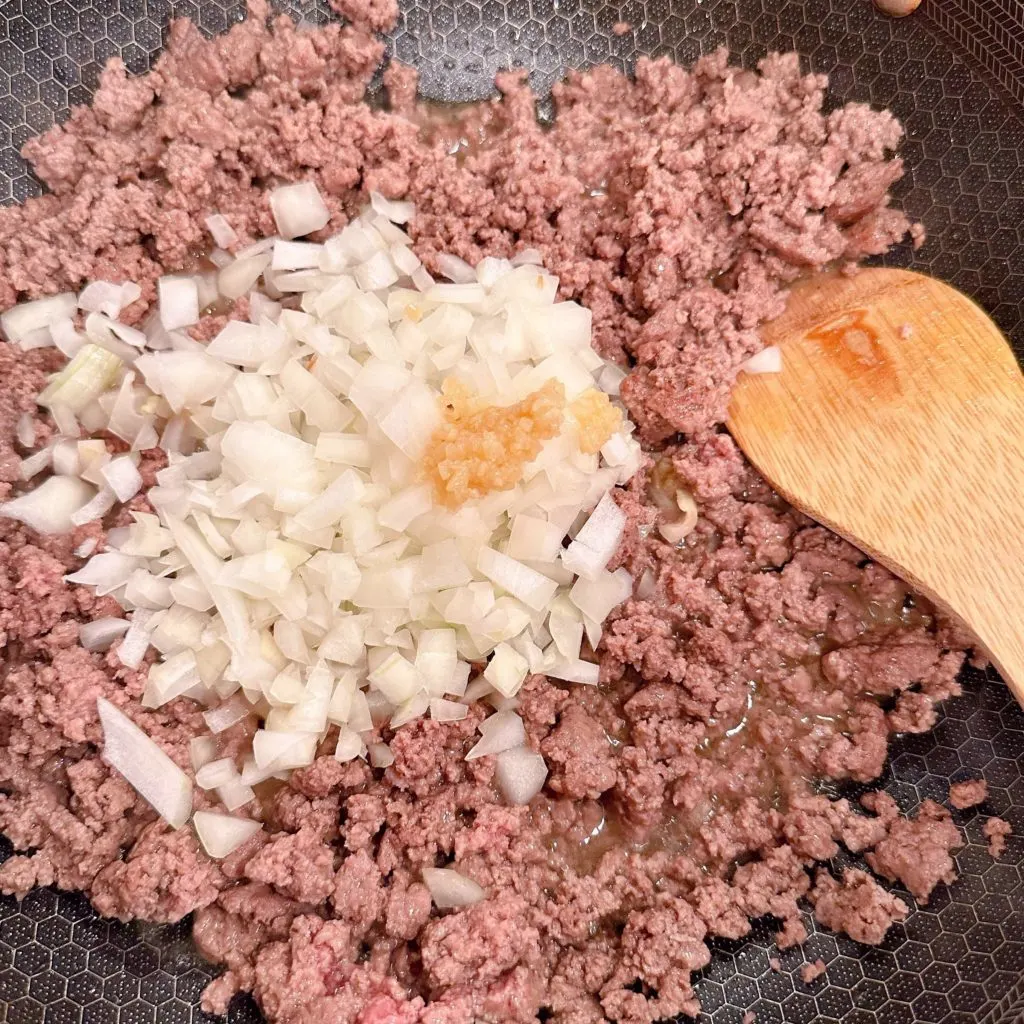 Browning ground beef with onions and garlic in a large skillet over medium-high heat.