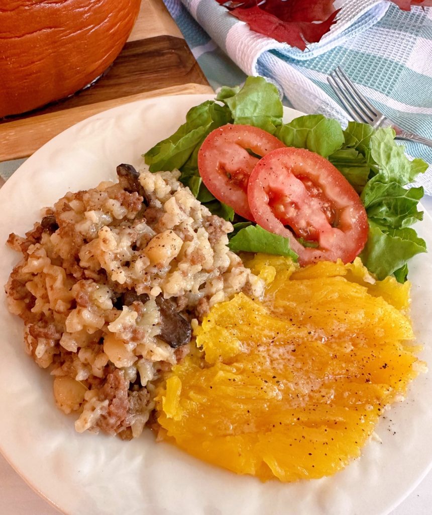 Serving plate with dinner in a pumpkin mixture, smashed squash, and a green salad.