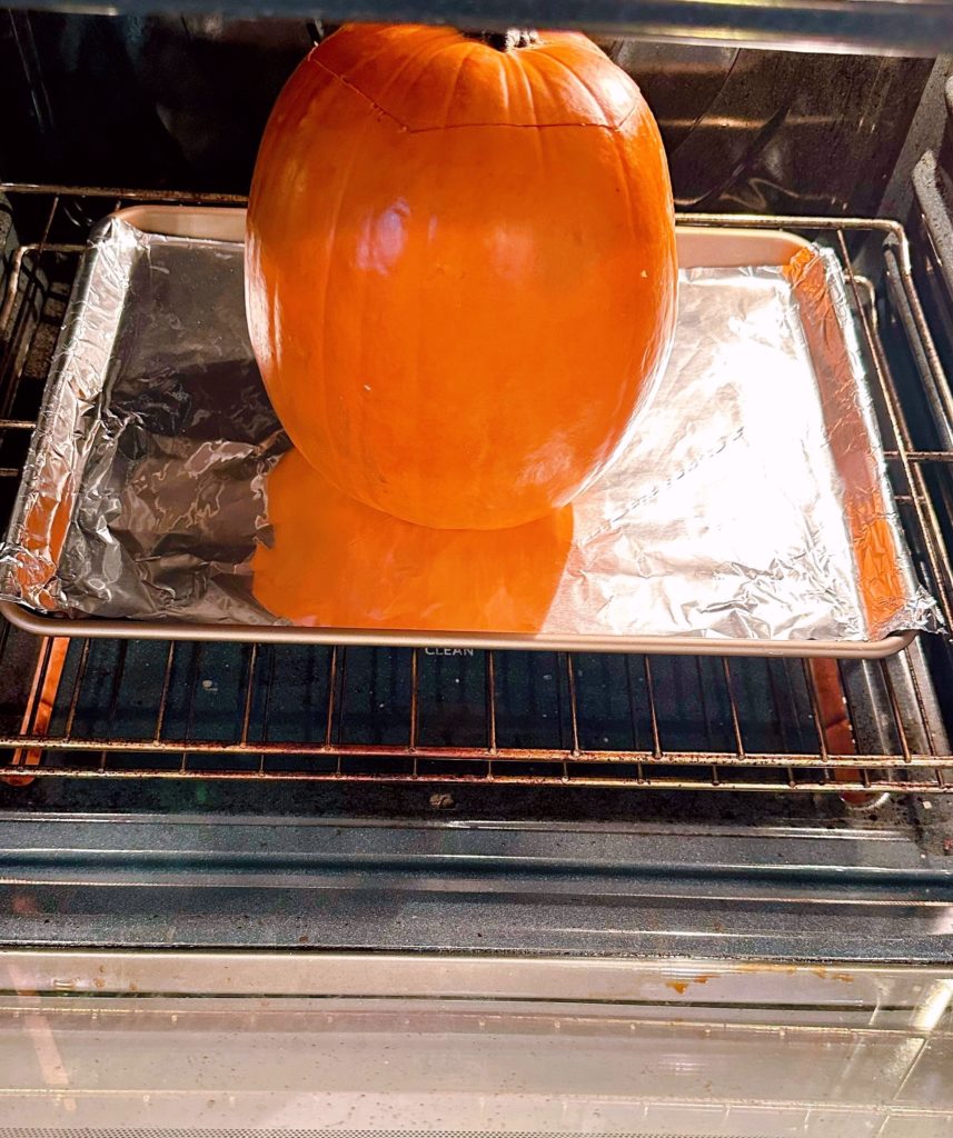 Pumpkin on baking sheet placed in the oven to bake.