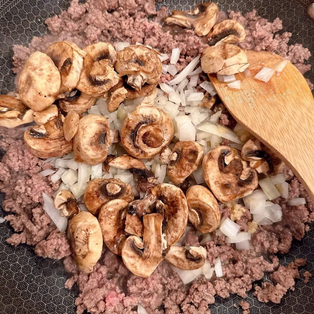 Adding Mushrooms, brown sugar, and soy sauce to meat mixture.