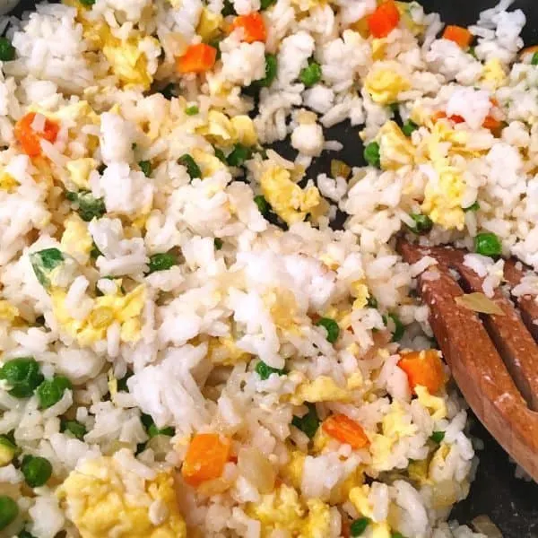 Adding rice to eggs and vegetables for fried eggs