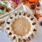 Overhead shot of decorated Pumpkin Chiffon Pie with pecan halves and whipped cream.