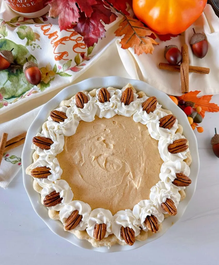 Overhead shot of decorated Pumpkin Chiffon Pie with pecan halves and whipped cream.