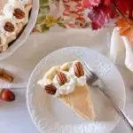 Slice of Pumpkin Chiffon Pie with pecan halves on a dessert plate.