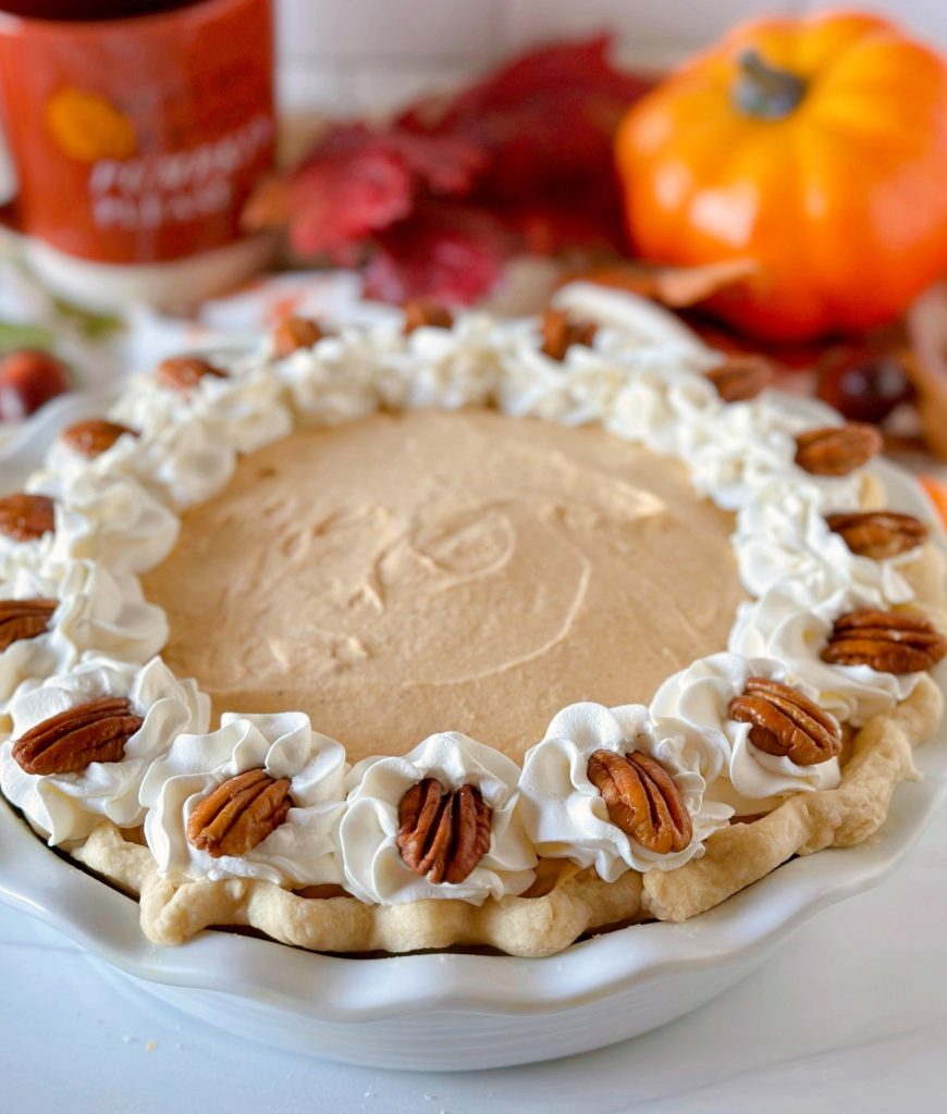 Whole Pumpkin Chiffon Pie with Whipped cream and pecan garnish.