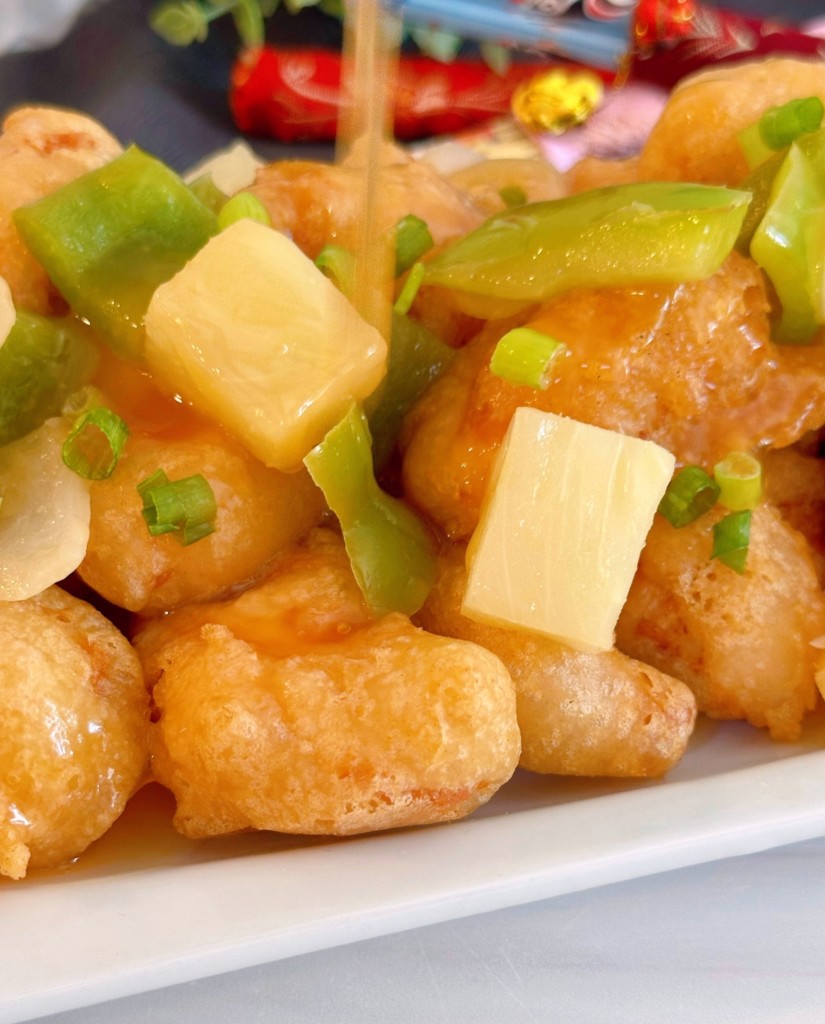 Sweet and Sour chicken on a white platter up close with veggies.