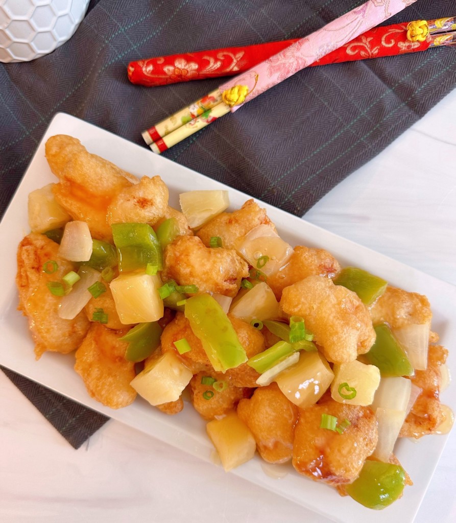 Overhead photo of full plate of sweet and sour chicken on a white serving platter.