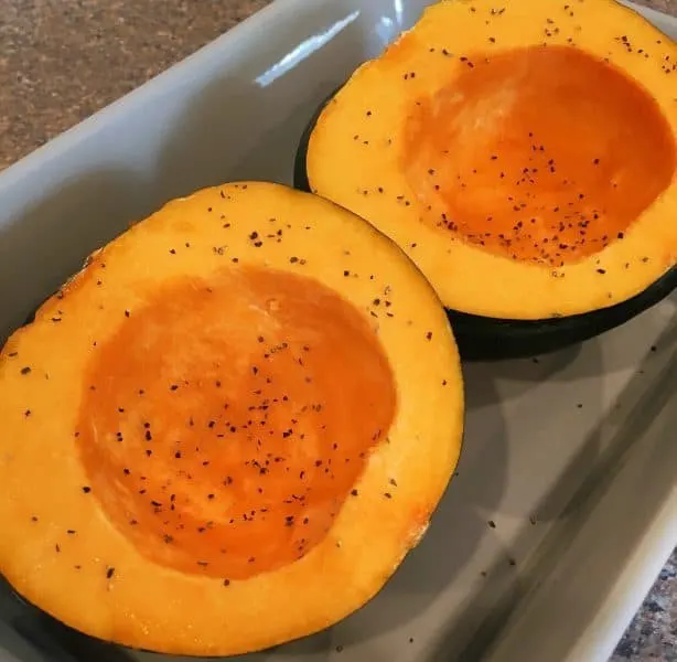 Acorn Squash cleaned and seeded, seasoned and in a casserole dish for baking