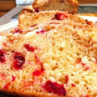 cranberry orange bread topped with crumb topping and orange drizzle